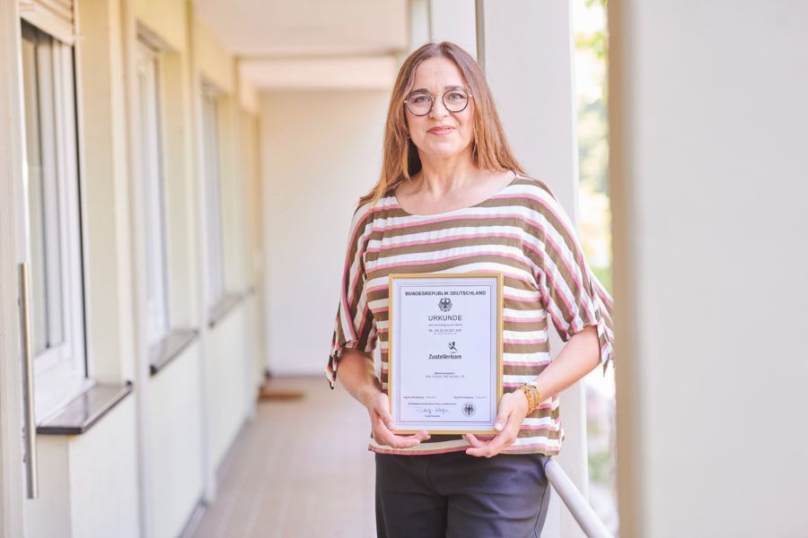 Christine Böck mit der Markenurkunde von Zustellerkom